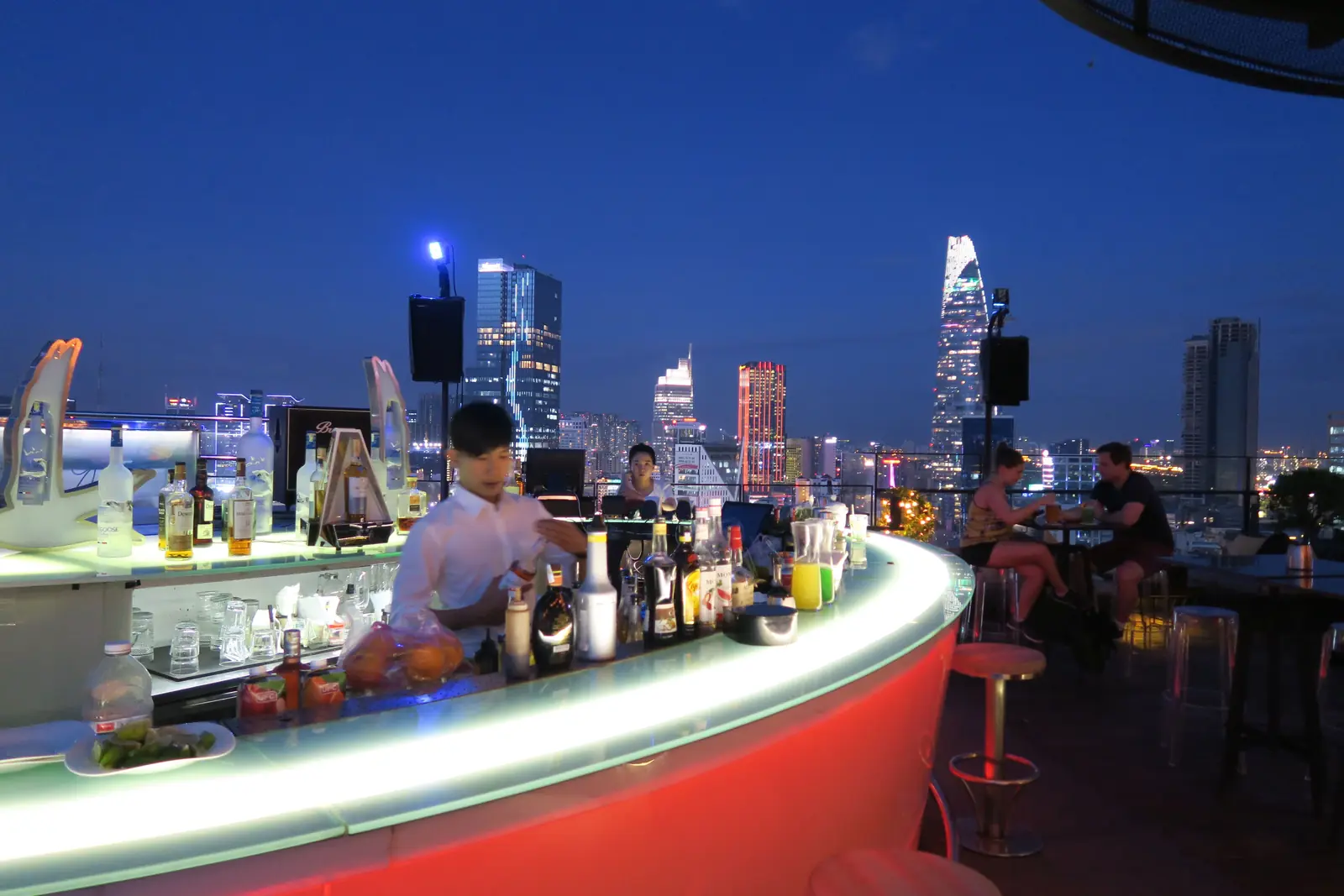 Rooftop-Bar vor der abendlichen Skyline von Saigon